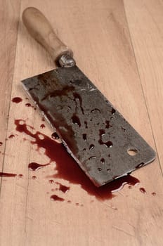 Old rusty meat cleaver with blood on a wooden floor