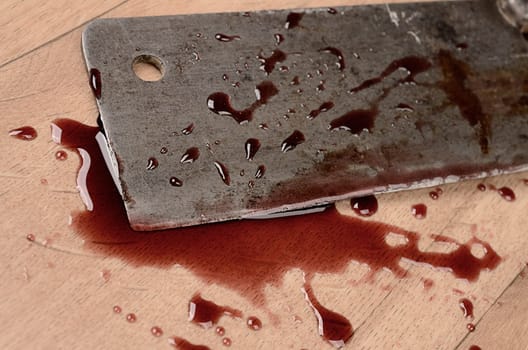 Old rusty meat cleaver with blood on a wooden floor