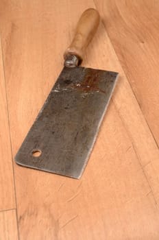 Old rusty meat cleaver on a wooden floor
