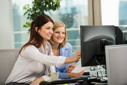 Beautiful businesswomen looking at computer monitor in office