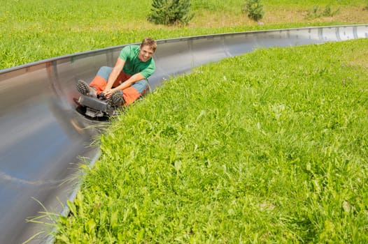 Happy young man enjoying alpine coaster luge during summer
