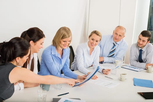 Business Team sitting around meeting table discussing file