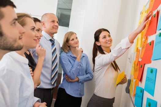 Businesswoman pointing  on whiteboard in meeting with office colleagues