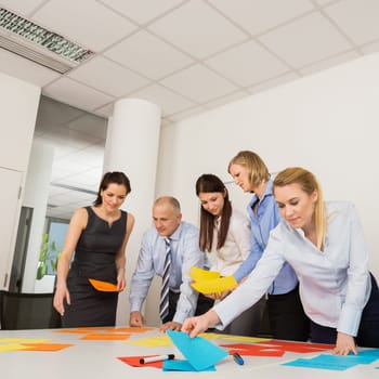 Business colleagues discussing multicolored labels in boardroom meeting