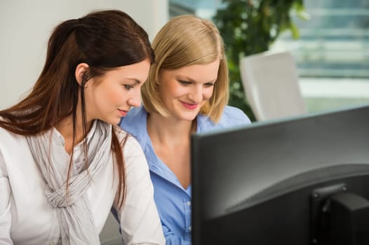 Young businesswomen looking at computer monitor in office