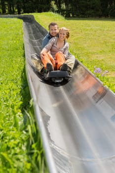 Portrait of happy couple enjoying alpine coaster luge during summer