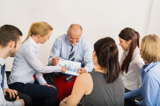 Business team discussing analysis graph sitting in meeting room
