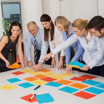 Business team brainstorming using color labels on table in office