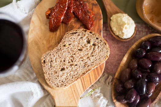 Slice of fresh whole wheat bread with olives, hummus and sun dried tomatoes.