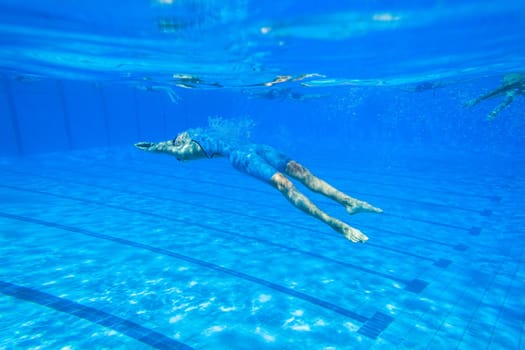 Swimmers girls boys warm-up laps before race heats.Underwater swimming water action at national championships.