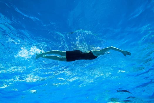 Swimmers girls boys warm-up laps before race heats.Underwater swimming water action at national championships.