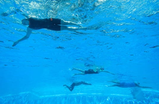 Swimmers girls boys warm-up laps before race heats.Underwater swimming water action at national championships.
