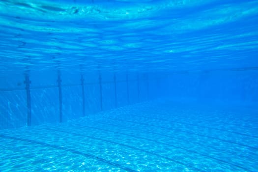 Underwater swimming pool waters towards surface and blue sky