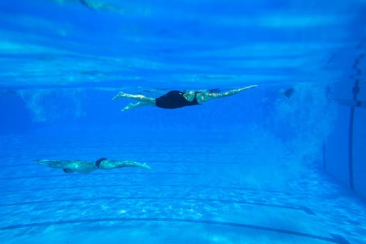 Swimmers girls boys warm-up laps before race heats.Underwater swimming water action at national championships.