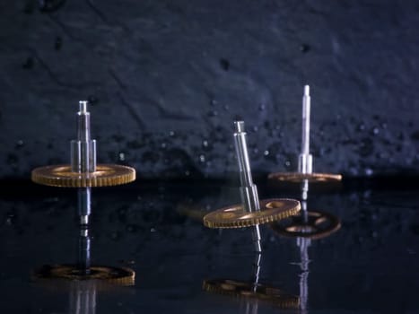 Close-up three fast-rotating gears on water-covered slate slab