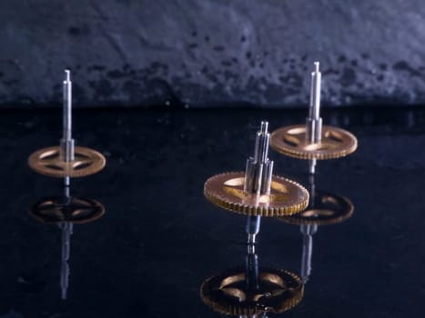 Close-up three fast-rotating gears on water-covered slate slab