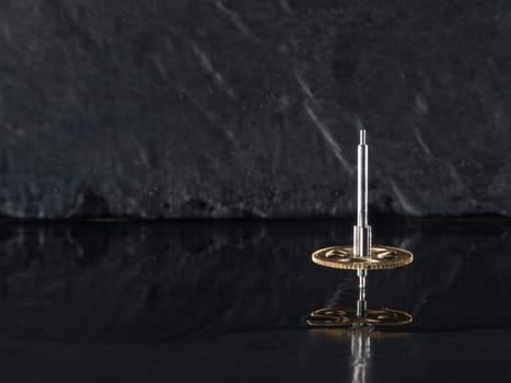 Close-up three fast-rotating gears on water-covered slate slab