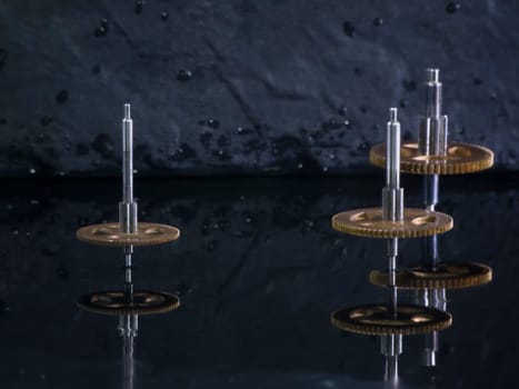 Close-up three fast-rotating gears on water-covered slate slab