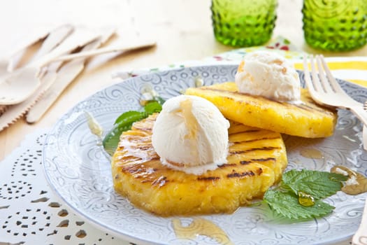 Grilled pineapple rings with ice cream balls and honey