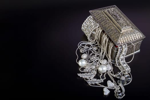 Silver jewelry on black background.
