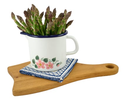 Bunch of green asparagus in enamel pot, isolated on white.