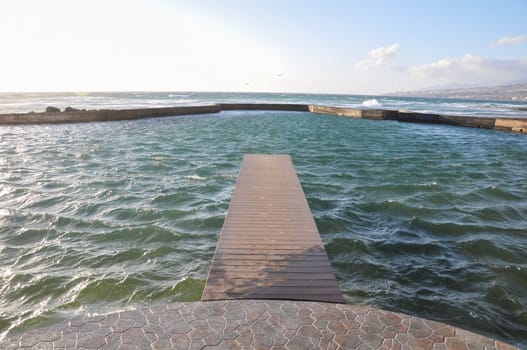 Empty Wooden Pier With Sea And Cloudy Sky On Background