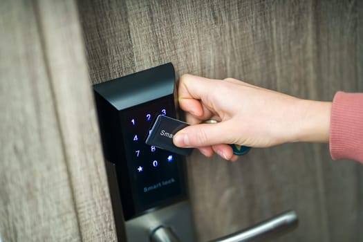A woman's hand applies a card, opens the door of a house, apartment with a technological modern lock with a code, close-up view, home security.