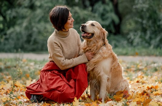 Young woman in autumn park with her golden retriever dog