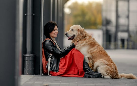 Young woman sitting outdoors with her golden retriever dog