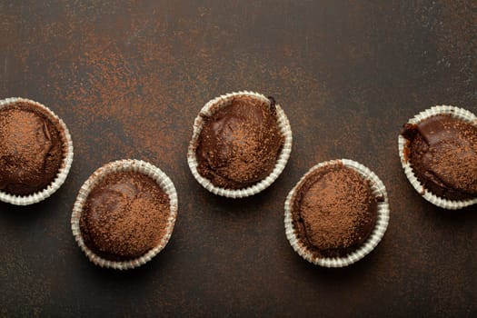 Chocolate and cocoa browny muffins top view on brown rustic stone background, sweet homemade dark chocolate cupcakes.