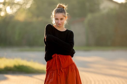 Beautiful teenager girl posing in park outdoors at nature. Pretty teen model in trendy clothes at street portrait