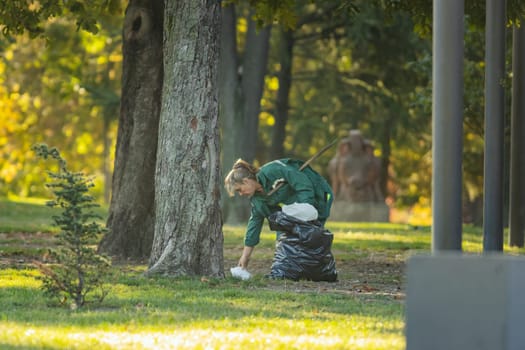 29 september 2023, Belgrade, Serbia - woman cleaner in the autumn city park undertake of plastic garbage, telephoto shot