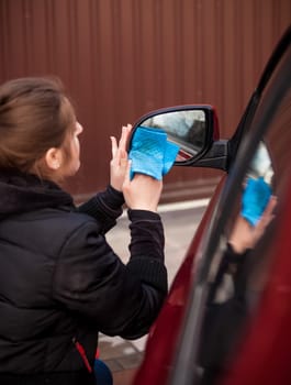 Closeup portrait of woman cleaning car mirror