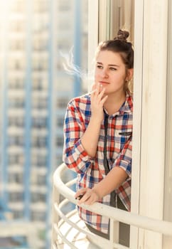 Toned portrait of beautiful woman smoking cigarette on balcony