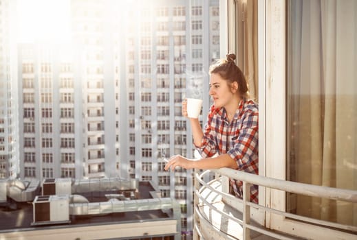 Portrait woman drinking coffee and smoking out of window