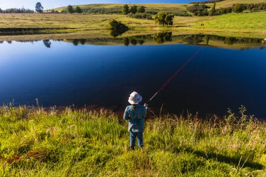 Young girl fishing in mountain dam on a  morning summer day
