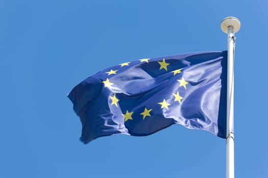 European Union flag fluttering in a brisk breeze against a blue sky
