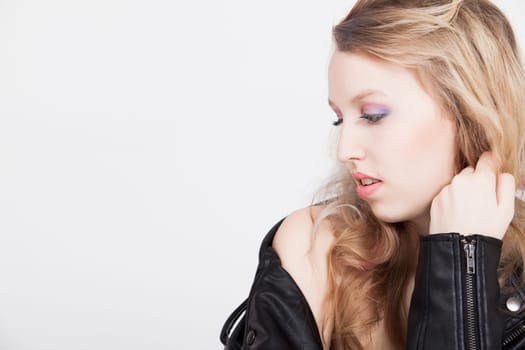 Young tough blond teenage girl with leather jacket on a white background