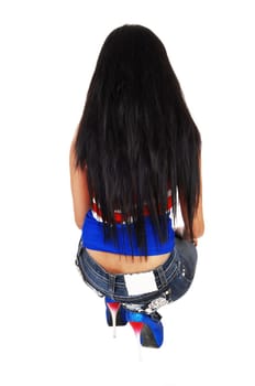 A skinny young woman kneeling isolated for white background from her .back in jeans and long black hair..