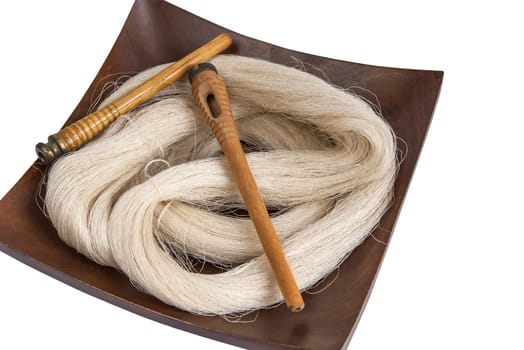 Raw silk yarn and spools of old loom in wooden platter