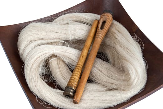 Raw silk yarn and spools of old loom in wooden platter