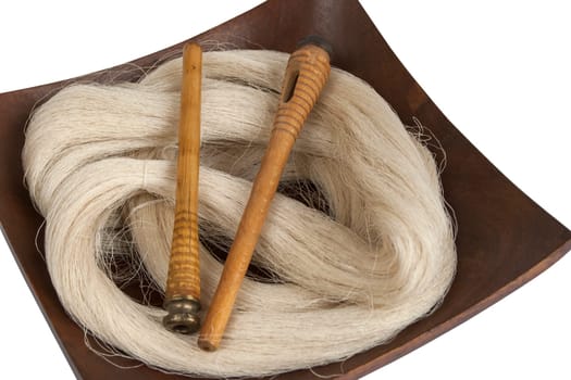 Raw silk yarn and spools of old loom in wooden platter
