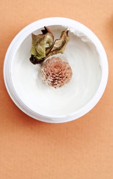 Spa essentials (cream and flowers) isolated on yellow