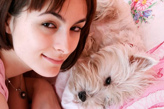 Westie sleeping next to woman in bed .