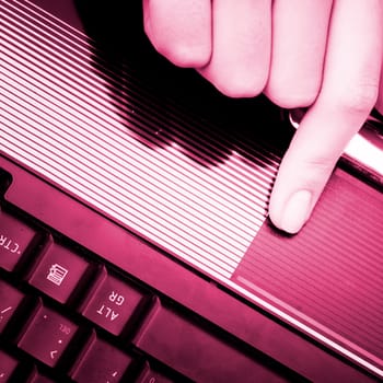 Closeup of woman's hand working at laptop.