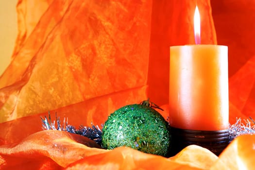 Green ball and candle isolated on orange