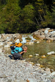 Hiker with backpack drinking water with hands