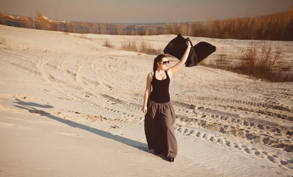 Beautiful slim woman posing at desert with black cloth