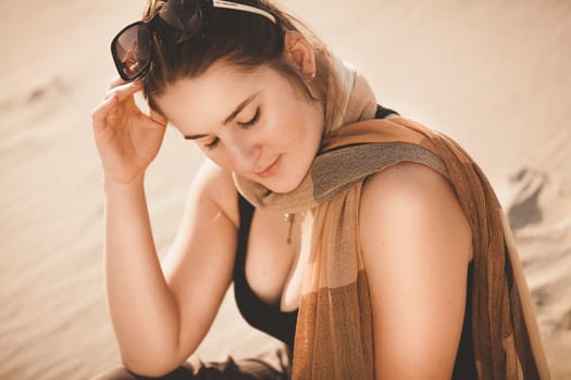 Closeup portrait of woman in sunglasses sitting on sand dune