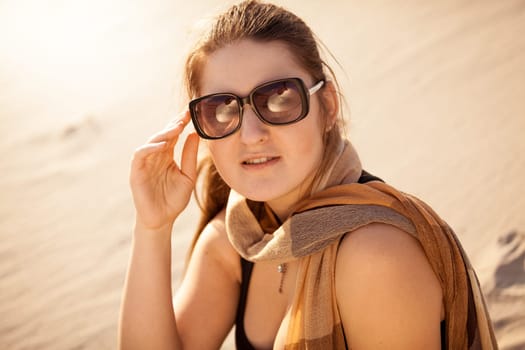 Closeup portrait of brunette woman in sunglasses at sunny day in desert